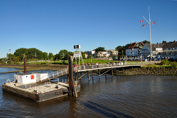 Wedel - Schulauer Fährhaus. Vorn auf der Brücke stehen die Lautsprecher, aus denen die Begrüßung oder die Verabschiedung zu den Schiffen hinüberschallt (Willkomm-Höft)	